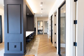 A long hallway with a table and chairs on the left and a glass door on the right.